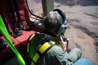 Archaeologist David Kennedy, who founded the Aerial Photographic Archive for Archaeology in the Middle East (APAAME) in 1978, can be seen taking pictures from a helicopter of various structures below.