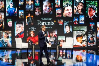 Prince Harry speaking at the Clinton Global Initiative in front of an image of phone lock screens