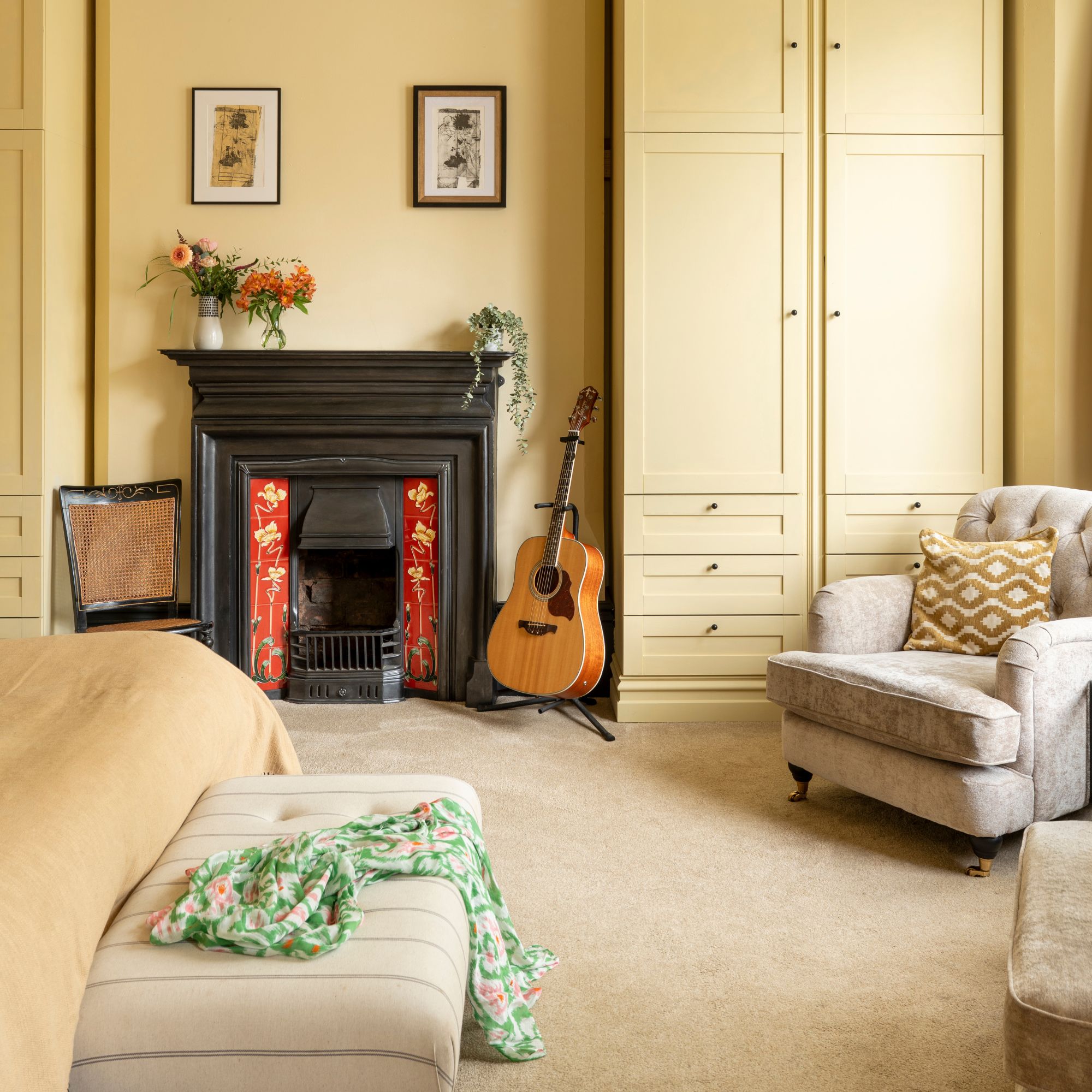 Yellow bedroom with a period fireplace in between yellow fitted wardrobes