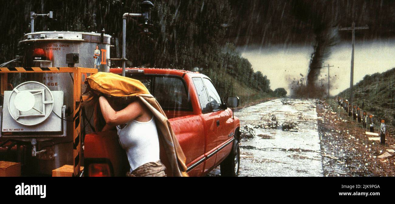 Uma mulher com uma capa de chuva sobre a cabeça ajusta o equipamento na traseira de um caminhão