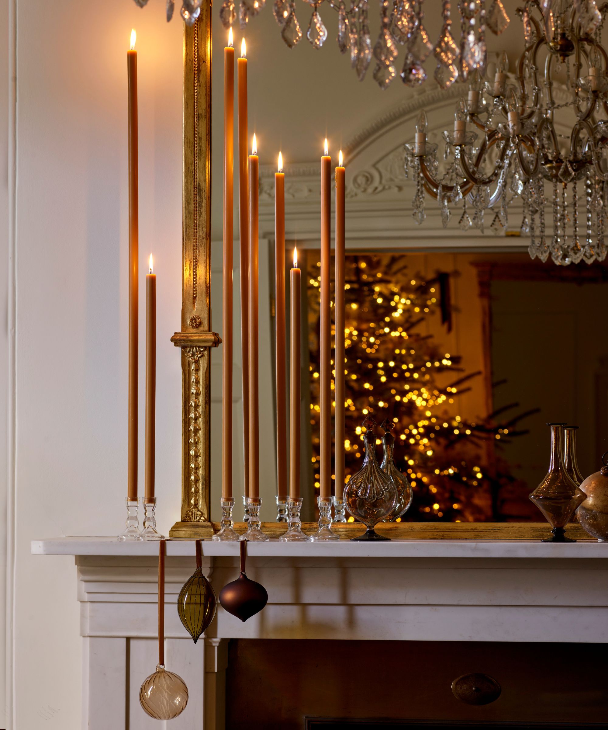 victorian home with neutral walls and fireplace with a gilt mantel mirror styled with tall taper candles and hanging baubles