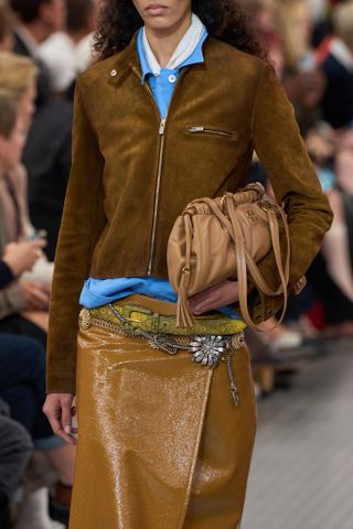 Schauen Sie sich die braune Wildleder-Reißverschlussjacke auf der Miu Miu-Modenschau Frühjahr/Sommer 2025 in Paris genau an.