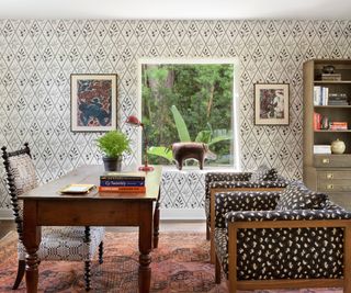 home office with patterned wallpaper and wood frame chairs with patterned upholstery