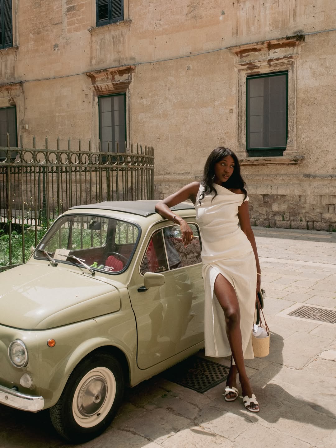 @emmanuellek_ wears an asymmetric midi dress, a basket bag and white slides