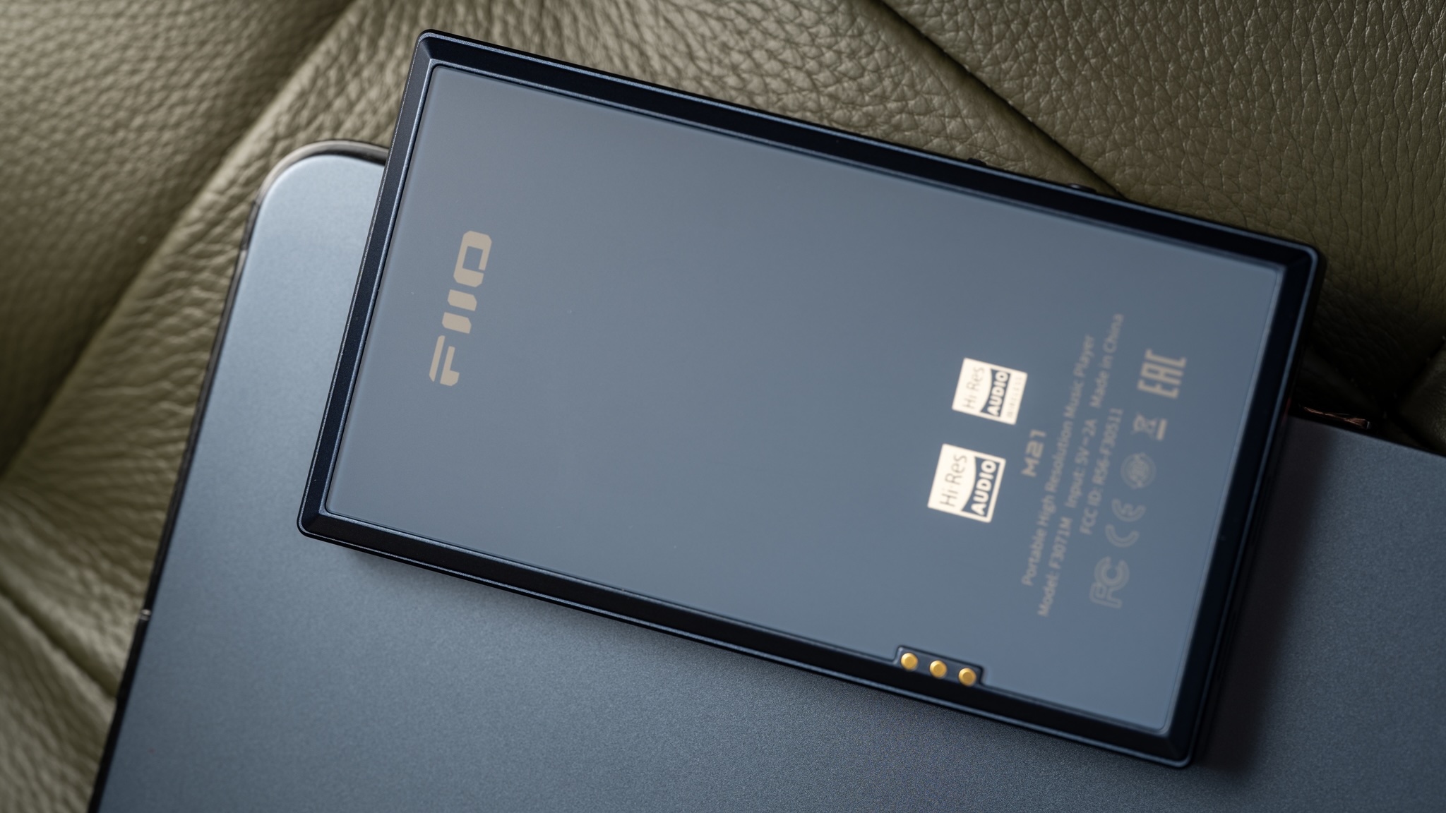 FiiO M21 music player lifestyle shot from above, showing the back of the player sitting on what looks like a tablet or laptop. There's not much going on here, the player is smooth and matte