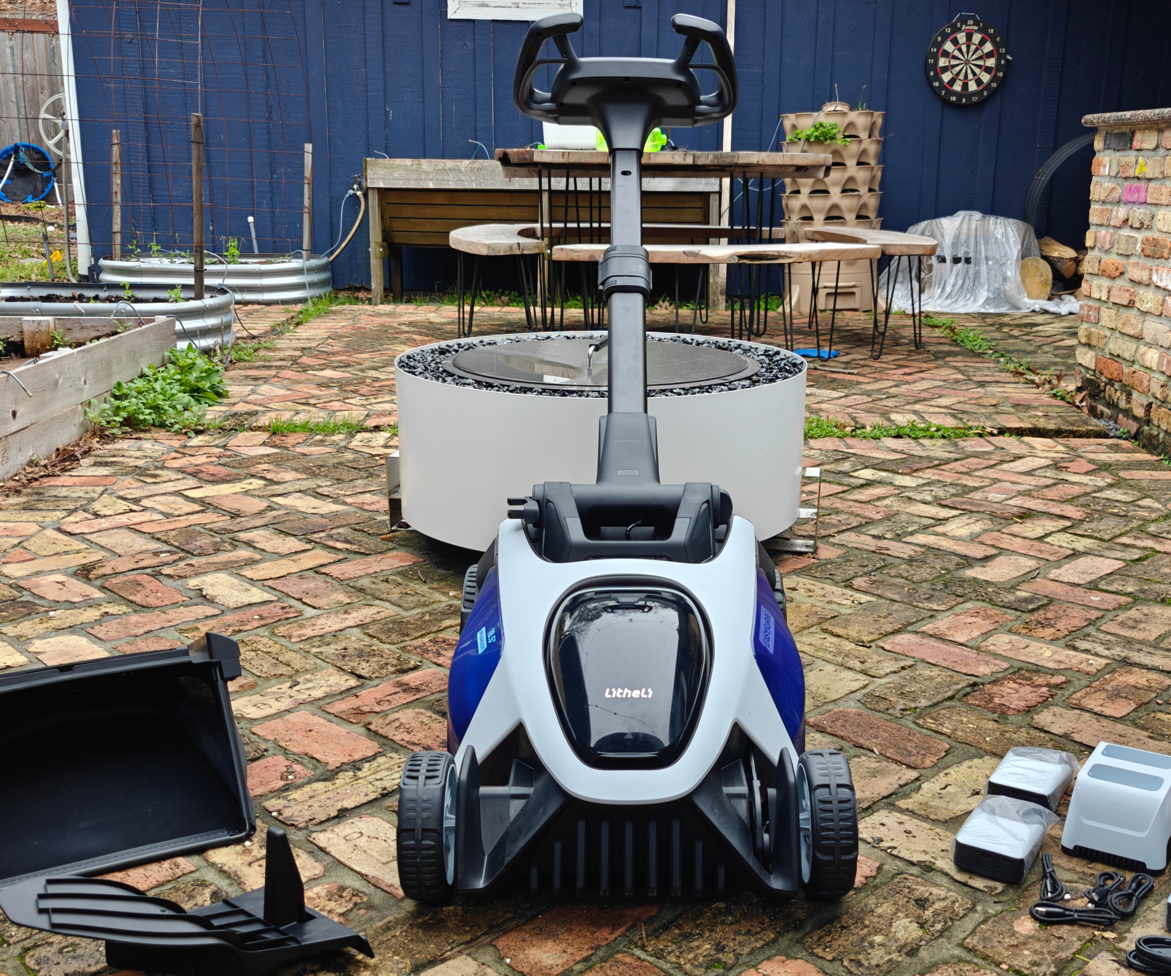 Liteli Easysurge Mower på murstein uteplass foran White Fire Pit