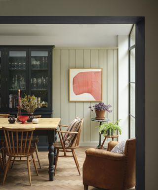 dining room with light green paneled walls, wooden table and dark gray dresser