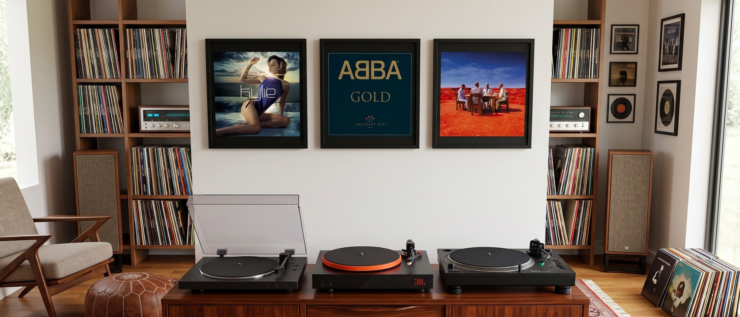 Three turntables on a media unit, with some records hanging on a wall behind.