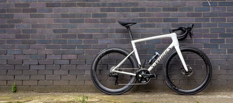 A white Specialized S-Works Tarmac SL8 stands against a wall