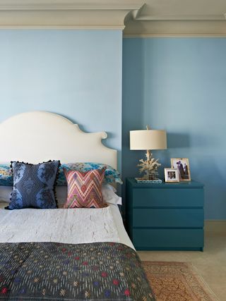 A blue toned bedroom with a teal painted drawer