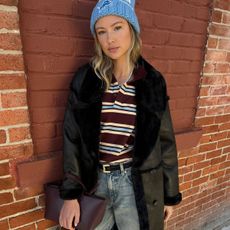 Woman in striped polo, hat, jeans, and coat