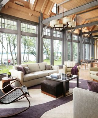 sitting room with wooden ceiling, neutral sofa and purple and white rug