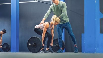 Woman learning how to deadlift properly with barbells