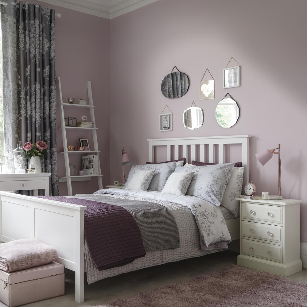 pink bedroom with white bed, mirrors on wall and ladder storage