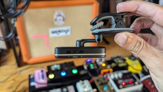 A man holds a Peterson Stroboclip HDC clip on tuner on its side in front of a guitar amp