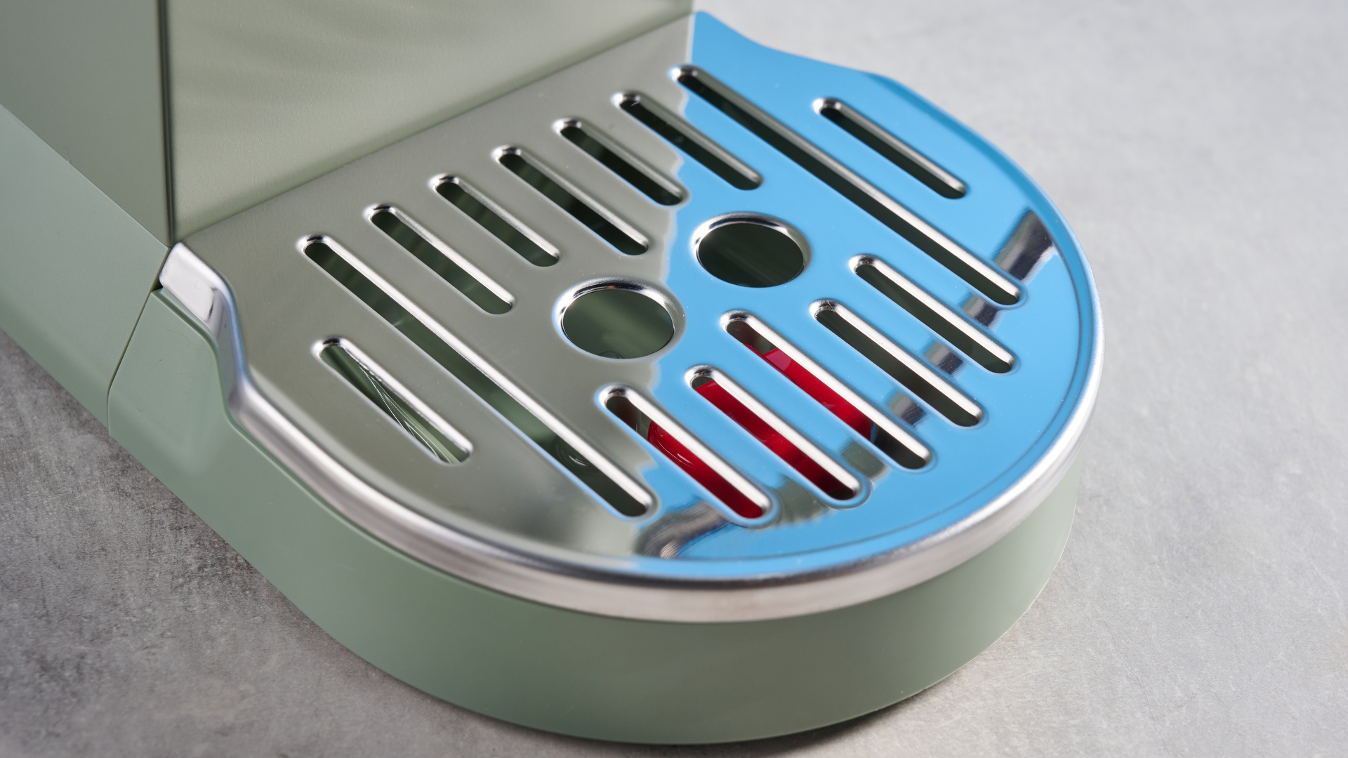 DeLonghi Dedica Duo in the green colorway with accessories photographed on a blue background.