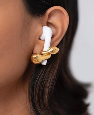 A photo of an AirPod being held in the ear by a specially designed earring called the AirPod.