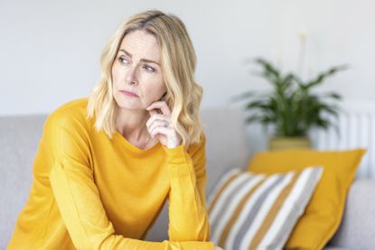 Thoughtful woman looking away while sitting at home