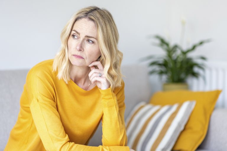 Thoughtful woman looking away while sitting at home