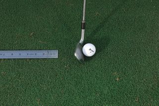 Placing a ruler behind the golf ball to work on strike