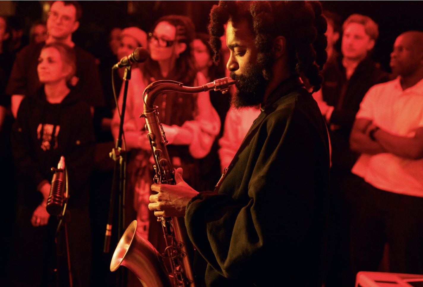 an image of a saxophonist playing in front of a crowd at a gig