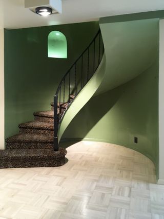 A green stairwell with a spiral staircase with leopard print carpet