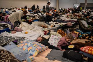 People rest in a temporary shelter for Ukrainian refugees, located near the Polish-Ukrainian border in a former shopping center in Przemysl, Poland, on March 8, 2022. - More than two million people have fled Ukraine since Russia launched its full-scale invasion less than two weeks ago, the United Nations said on March 8, 2022. Poland alone has received nearly half of all those fleeing Ukraine, with figures dated March 8, 2022 showing that 1,2 million had crossed into the country in the past 13 days.