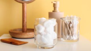 Cotton balls in a glass jar next t cotton buds, soap and a mirror