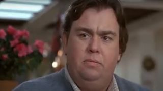John Candy sits with a straight face at the kitchen table in Uncle Buck.