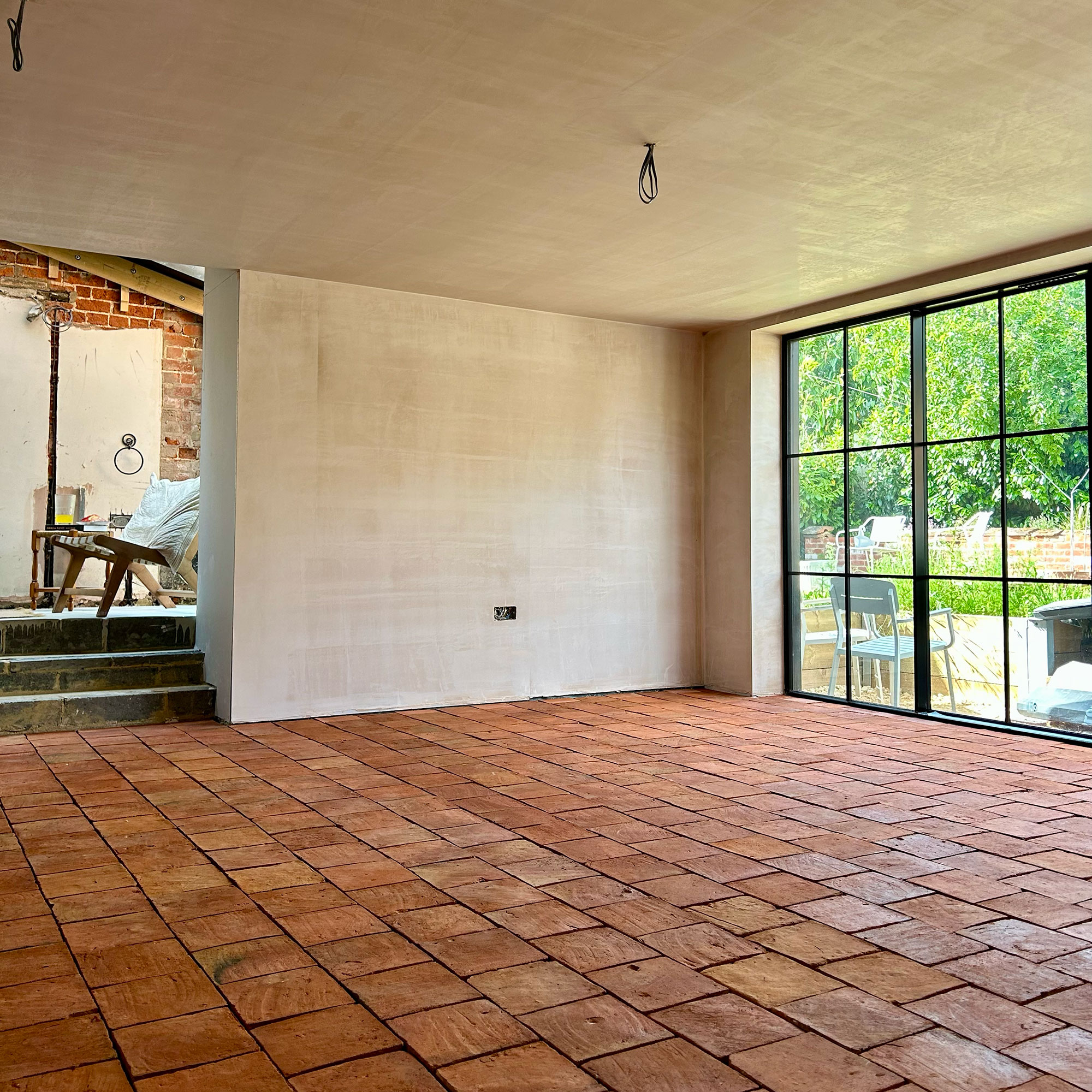 Empty room with bare walls and unfinished lighting with terracotta tiled floors