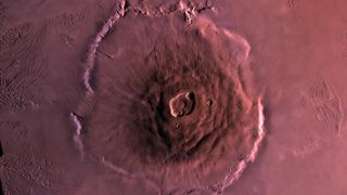Bird's-eye view of Olympus Mons. The enormous volcano rises up from the barren landscape, with a large crater at the center.