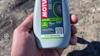 Close up of hand holding bottle of Motul Chain Lube Dry