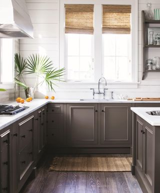 brown and white kitchen with dark wood flooring, coir rug, blind, shiplap walls, marble countertop, chrome faucet,