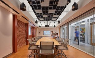 Meeting room at La Kretz with wooden table, chairs exposed brick wall and black industrial lights
