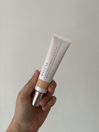 mica holding the Beauty Pie Luminous Mineral Skin Tint Broad-Spectrum SPF 40 Sunscreen