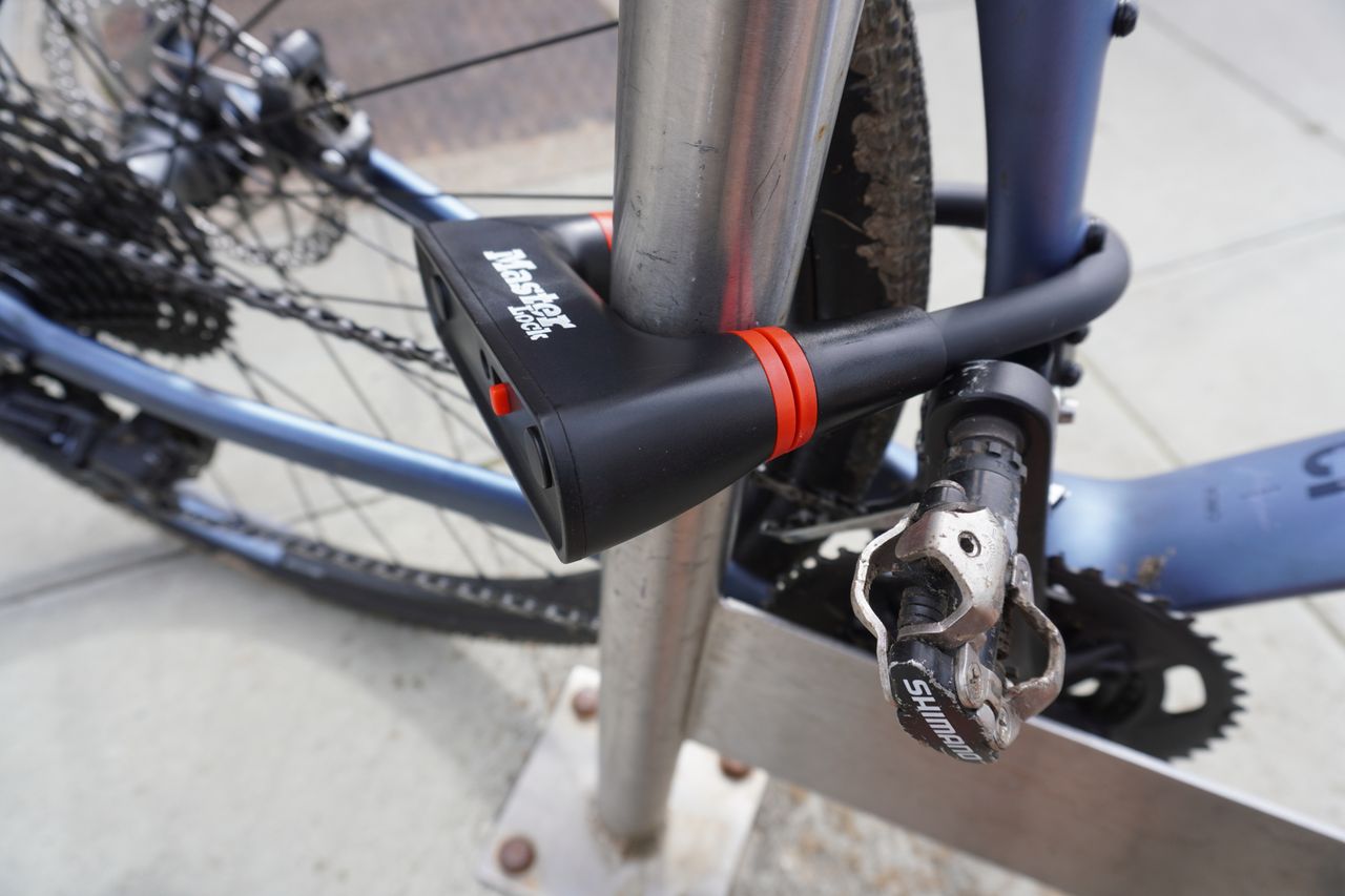 A road bike is shackled to a bike stand with a Master Lock Mini U-Lock 