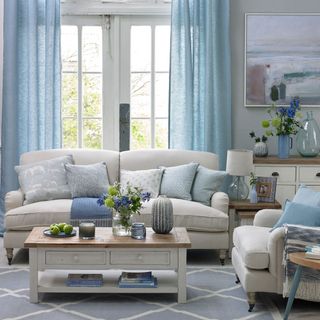 A duck egg blue living room with white sofa and white wooden coffee table