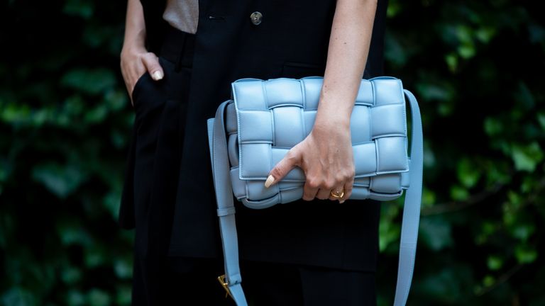 street style model holding one of the best designer bags by Bottega Veneta