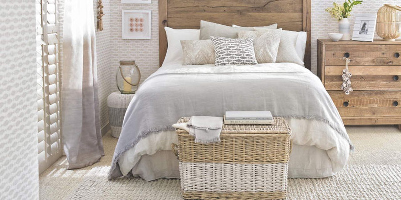 A cream and wooden bedroom with a bed and valance in the centre