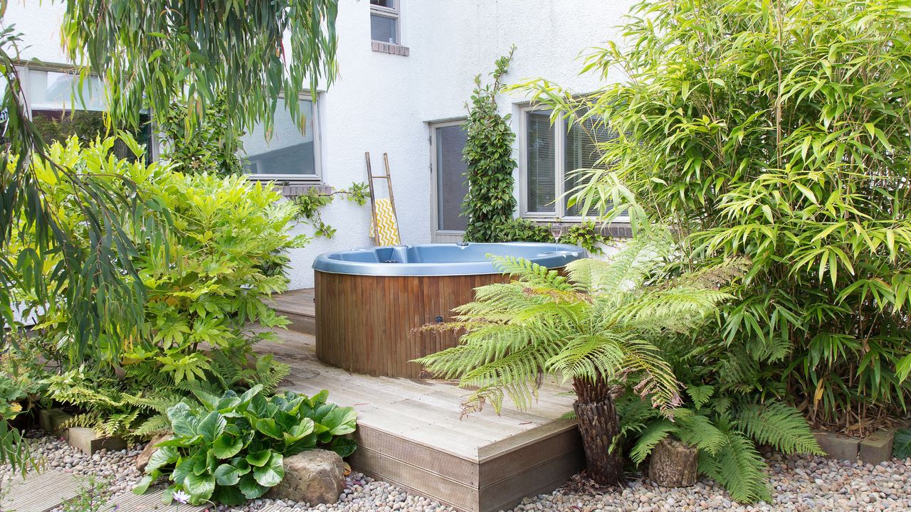 Hot tub sitting on a wooden deck surrounded by plants