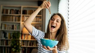 Woman looks happy as she holds up a big bowl of food