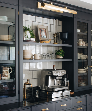 A navy blue coffee bar with a silver coffee machine and a built-in sink.