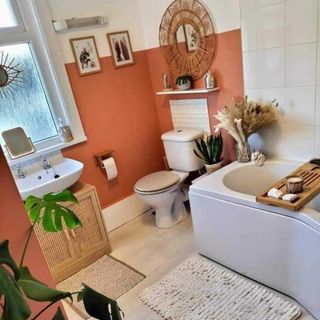 bathroom with rattan mirror and terracotta walls