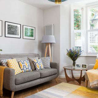 White living room with grey and yellow sofa, armchair, accessories and rug