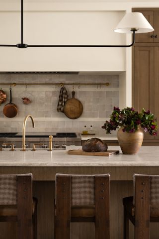 Three bar stools are set at a stone kitchen island