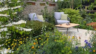 small patio space at Chelsea Flower Show featuring two armchairs and a low patio coffee table