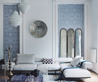 A living room with white walls and alcoves decorated with blue and white patterned wallpaper