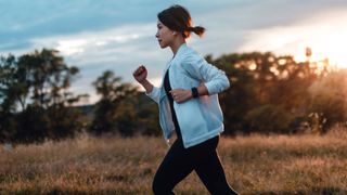 Is running cardio? Image shows young woman running in the park at sunset