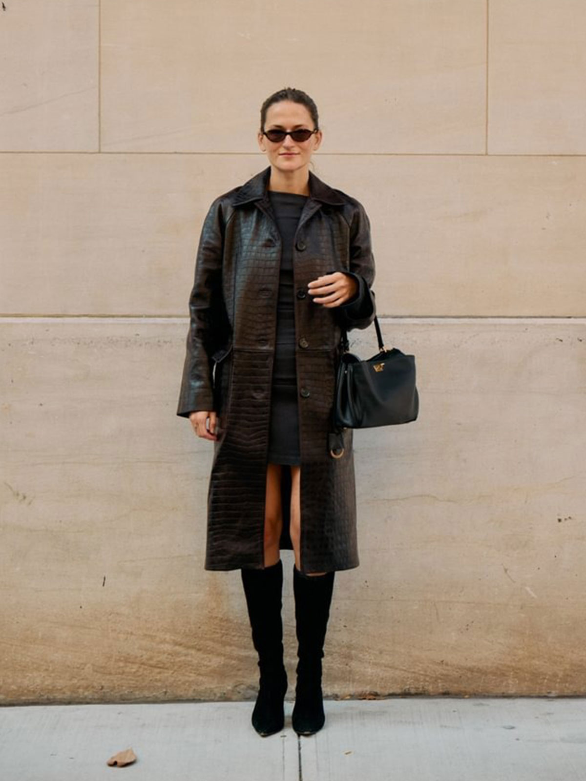 Woman wearing a long brown croc-leather coat.