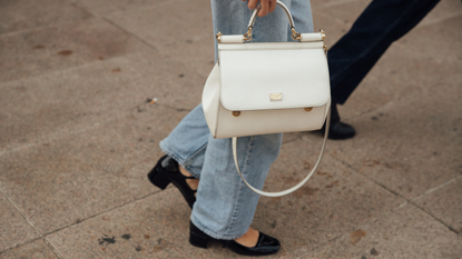 White top handle bag with jeans and black mary jane shoes 